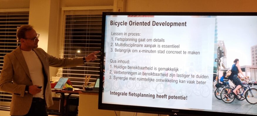 Foto waar Paul van de Coevorden zijn presentatie geeft voor een dia op het scherm met de titel 'Bicycle Oriented Development'