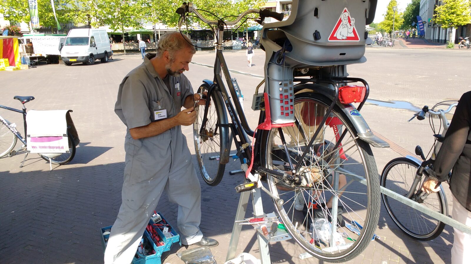 Vrijwilliger aan het werk aan de dynamo van een fiets. Strijdkrachtige pose, geconcentreerde blik.