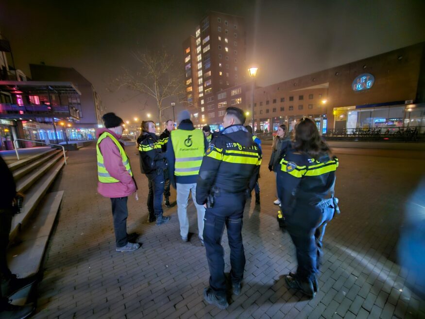 Politieagenten en mensen in veiligheidsjasjes in het donker op de stoep voor het gemeentehuis Houten.